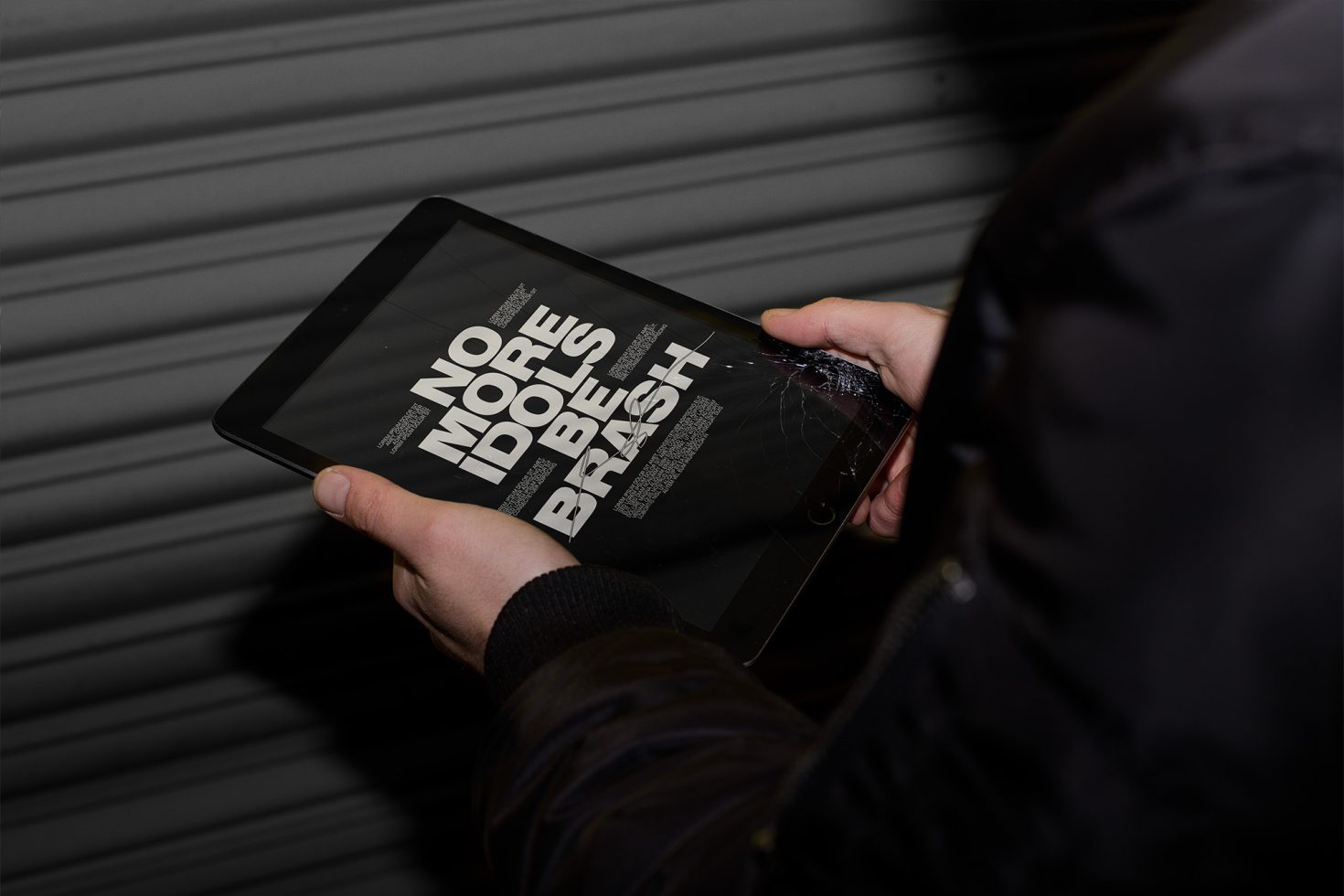 Person holding a broken tablet displaying bold typography design, potential mockup for digital assets showcasing font styles and design presentation.